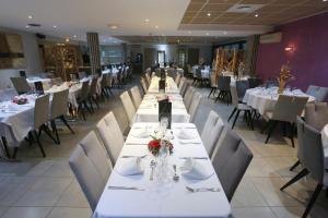 une grande salle à manger avec des tables et des chaises blanches dans l'établissement Aeroport Hotel - Parc Expo, à Mauguio