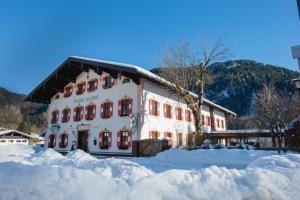 ein großes weißes Gebäude mit roten Fenstern im Schnee in der Unterkunft Posthotel Sachrang in Sachrang