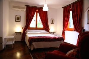 パレルモにあるAl Colle dei Principiのベッドルーム1室(ベッド1台付)、赤いカーテン付きの窓2つが備わります。