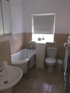 a bathroom with a tub and a toilet and a sink at Westport Holiday Home in Westport