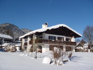 ein Haus mit schneebedecktem Dach im Schnee in der Unterkunft Ferienwohnung Erna Heigermoser in Ruhpolding