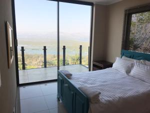 a bedroom with a bed and a large glass window at Thatch View in Hartbeespoort