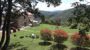 a garden with a house and mountains in the background at Agriturismo la Coccinella in Poggioni