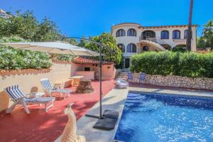 a house with a swimming pool with an umbrella and some chairs at Paul - modern, well-equipped villa with private pool in Benissa in Benissa