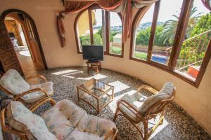 sala de estar con sillas, TV y ventanas en Paul - modern, well-equipped villa with private pool in Benissa, en Benissa