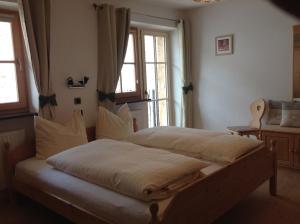 two beds in a bedroom with two windows at Biohof Hamann in Sarntal