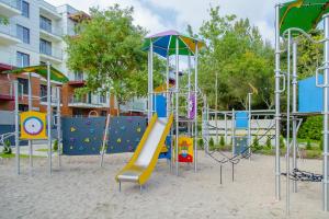 un parque infantil con un tobogán en la arena en Apartament Baltic Polanki Park Kołobrzeg, en Kołobrzeg