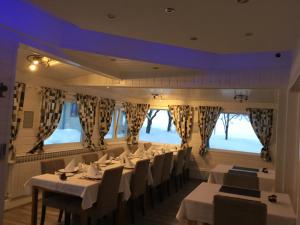 a restaurant with white tables and chairs and windows at House Zupan in Rakovica
