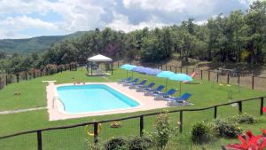 a swimming pool in a yard with chairs and umbrellas at Agriturismo la Coccinella in Poggioni