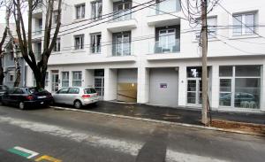 two cars parked in front of a white building at Apartment Iris in Belgrade