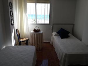 オロペサ・デル・マールにあるEdificio Las Rocasのベッドルーム1室(ベッド2台、テーブル、窓付)