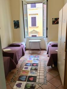 ローマにあるジダン ゲストハウスの紫色のベッド、テーブル、窓が備わる客室です。