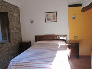 een slaapkamer met een bed met een gestreepte deken bij Mas el Llach in La Vall de Bianya