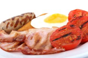 a white plate topped with eggs, sausage, bacon and tomatoes at Adelphi Portrush in Portrush