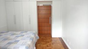 1 dormitorio con 1 cama y puerta de madera en Village Copacabana en Río de Janeiro
