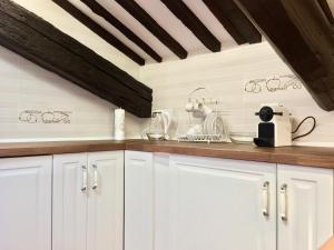 a kitchen with white cabinets and a wooden ceiling at Dietro le volte in Ferrara