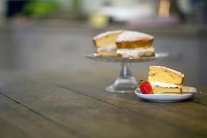 un plato de pastel con una fresa en una mesa en Meadowsweet Cottage, Drift House Holiday Cottages, en Astbury