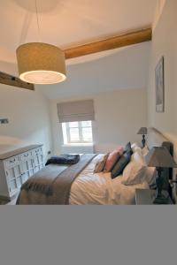 um quarto com uma cama, um candeeiro e uma janela em Meadowsweet Cottage, Drift House Holiday Cottages em Astbury