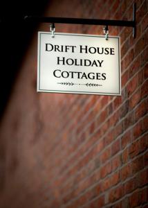 a sign that reads drift house holiday coffees hanging on a brick wall at Meadowsweet Cottage, Drift House Holiday Cottages in Astbury
