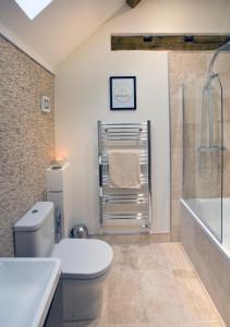 a bathroom with a toilet and a shower and a tub at Meadowsweet Cottage, Drift House Holiday Cottages in Astbury