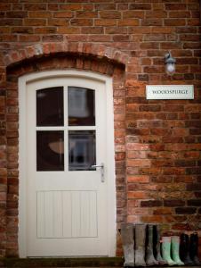 a white door in a brick wall with boots at Meadowsweet Cottage, Drift House Holiday Cottages in Astbury