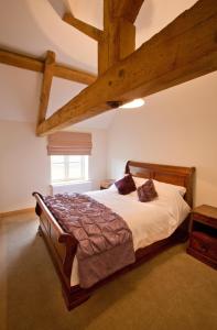 a bedroom with a large bed with wooden beams at Meadowsweet Cottage, Drift House Holiday Cottages in Astbury