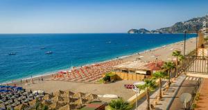una spiaggia con sedie e ombrelloni e l'oceano di Hotel Caudullo a Letoianni