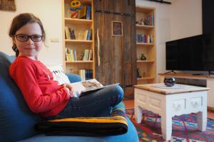 a woman sitting on a couch reading a book at Zur Scheune in Ilmenau