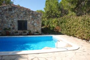 a swimming pool in front of a stone house at Casa Estany in L'Ametlla de Mar