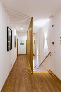 um corredor com paredes brancas e pisos de madeira e uma escadaria em H18 em Horta