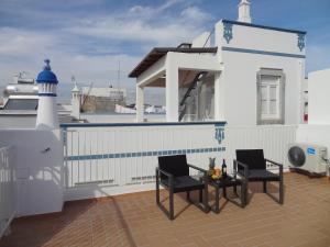 a balcony with two chairs and a table and a lighthouse at Fisherman's Palace in Olhão