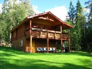 a large log cabin with a deck on a lawn at Shadow Mountain Cabins in Riondel