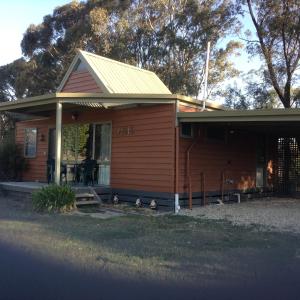 una pequeña casa con patos parados fuera de ella en Glenfield Cottage, en Yarck