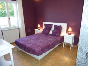um quarto com uma cama roxa com 2 mesas e 2 candeeiros em le petit coin de Noah em Châteauneuf-Val-Saint-Donat