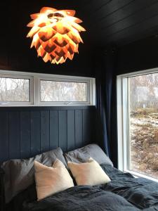 a bedroom with a bed and a chandelier and two windows at Steigen Lodge Sjøhytter in Engeløya