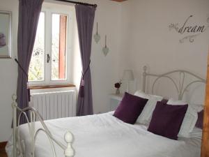 a bedroom with a white bed with purple pillows at Cottage in Auvergne in Laval-sur-Doulon