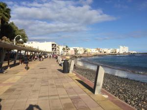 people walking on a sidewalk next to the beach at Sol y mar in Arinaga