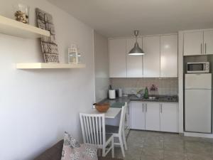 a kitchen with white cabinets and a table and a refrigerator at Sol y mar in Arinaga
