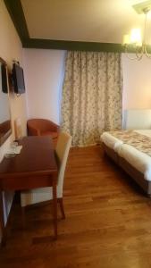 een hotelkamer met een bed, een bureau en een tafel bij Hotel Pelasgos in Karítaina