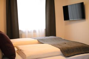 a bedroom with two beds and a flat screen tv at Boutique Hotel Beckenlehner in Unterhaching