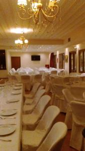 um salão de banquetes com cadeiras brancas e um lustre em Hotel Pelasgos em Karytaina