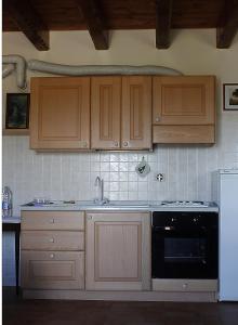 una cucina con armadi in legno, lavandino e piano cottura di Agriturismo Prato Grande a Loiano