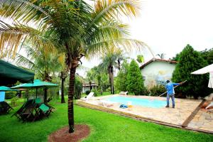 un uomo è in piedi accanto a una piscina di Pousada Akonxego a Olímpia