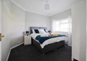 a white bedroom with a bed and a window at Grove Cottage in Basingstoke