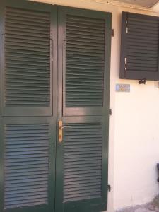 une paire de portes vertes sur le côté d'un bâtiment dans l'établissement Appartamento Poggio Romantico Andrea, à Marciana