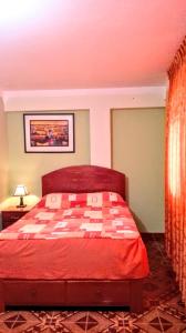 1 dormitorio con cama roja y colcha a cuadros en Residencial Norandes, en Huaraz