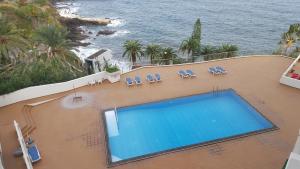 einen Blick über einen Pool mit Stühlen und das Meer in der Unterkunft Apartamento Vista Mar e Piscina in Funchal
