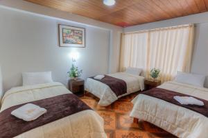 a room with three beds in a room with a window at Machupicchu Guest House in Machu Picchu