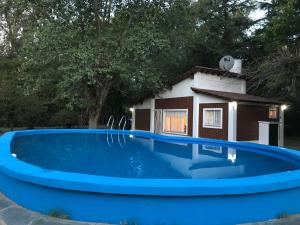 una gran piscina azul con una casa en el fondo en Chalet con piscina en Chivilcoy