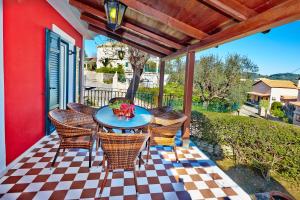 un patio con mesa y sillas en una pared roja en Anemelia' Villa en Áyios Dhimítrios